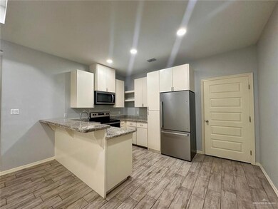 Kitchen with appliances with stainless steel finishes, a peninsula, light stone countertops, a breakfast bar area, and light wood-style floors