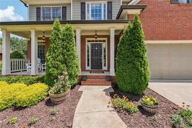 Doorway to property with brick siding, a garage, a porch, and concrete driveway