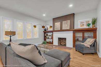 Living room featuring light wood-style floors, a brick fireplace, and recessed lighting