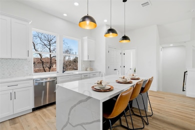 Gorgeous kitchen with quartz counters, white shaker cabinets, marble mosaic backsplash, and large picture windows that flood the space with natural light.