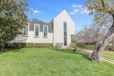 View of side of home with a lawn and roof with sh