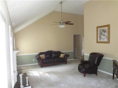 Large open living area with vaulted ceilings, ceiling fan and fireplace.