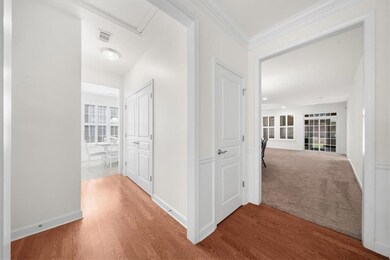 Hall with wood finished floors, crown molding, and baseboards