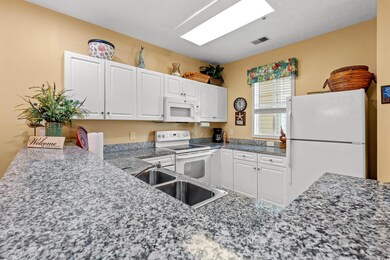 Kitchen with white appliances, a sink, and white c
