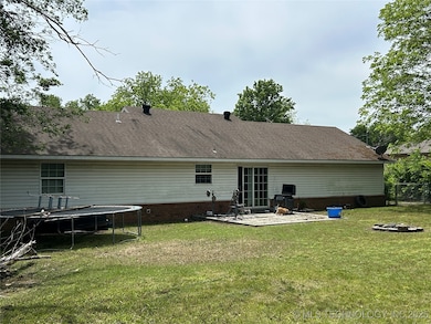 Back of house with a trampoline, a patio, a fire p