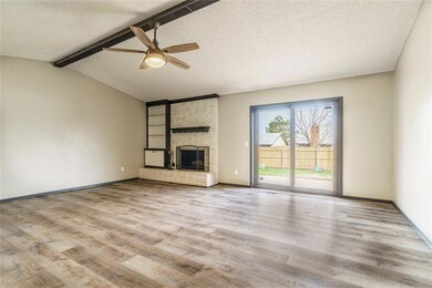 Unfurnished living room with brick wall, a fireplace, lofted ceiling with beams, light hardwood / wood-style flooring, and ceiling fan