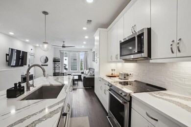 Kitchen with appliances with stainless steel finishes, a sink, white cabinets, hanging light fixtures, and ceiling fan