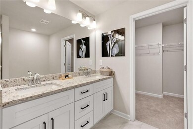 Full bathroom with a spacious closet, baseboards, and double vanity