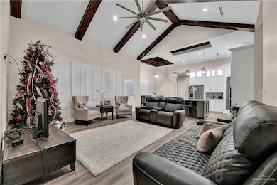 Living area featuring high vaulted ceiling, light wood-type flooring, and beam ceiling