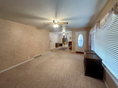 Foyer with a ceiling fan, light colored carpet, a textured ceiling, and wallpapered walls