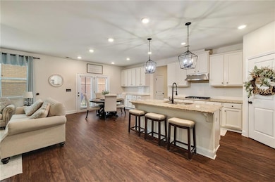 Kitchen with a sink, a breakfast bar, recessed lighting, plenty of natural light, and under cabinet range hood