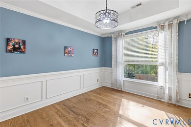 Empty room with a wainscoted wall, a decorative wall, wood finished floors, crown molding, and a chandelier