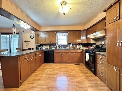 Kitchen with sink, black appliances, light hardwoo