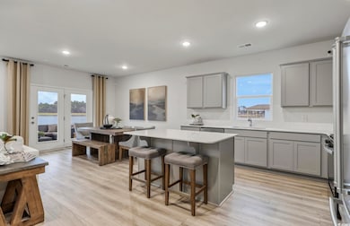 Kitchen featuring gray cabinets, a breakfast bar area, a kitchen island, decorative backsplash, and stainless steel refrigerator