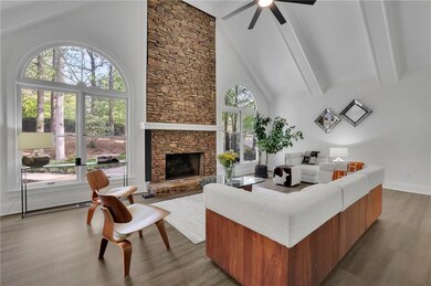 Living area featuring wood finished floors, beam ceiling, a fireplace, high vaulted ceiling, and ceiling fan