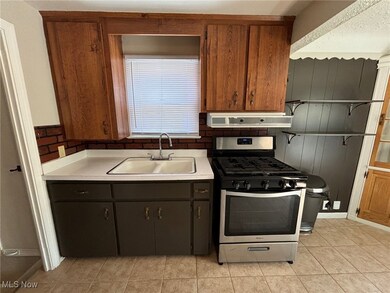 Kitchen featuring light tile patterned floors, sink, extractor fan, and stainless steel gas range