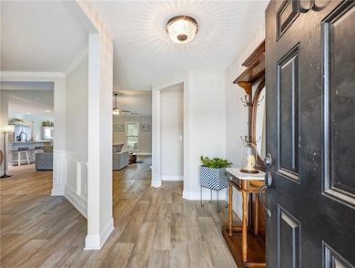 Foyer with light wood-style floors, a ceiling fan, and ornamental molding