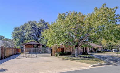 View of front of home with a gate, concrete driveway, and brick siding