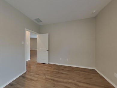 Spare room featuring wood finished floors and bas