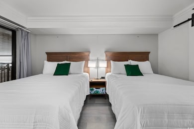 Bedroom with hardwood / wood-style floors, a barn door, and crown molding