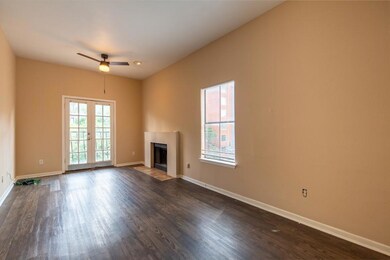 Unfurnished living room featuring a fireplace with flush hearth, dark wood-style floors, french doors, and a ceiling fan