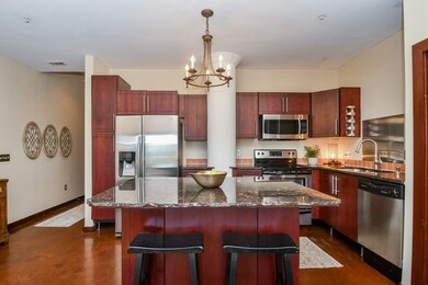 A granite-topped island with a custom chandelier b