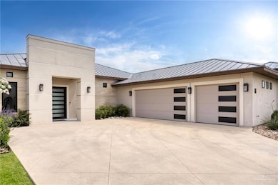 Contemporary house with a standing seam roof, metal roof, driveway, a garage, and stucco siding