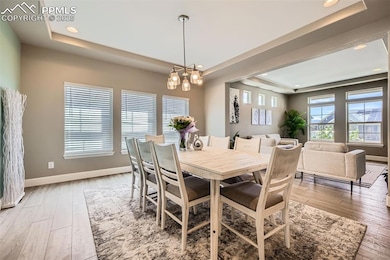 Dining area featuring a raised ceiling, recessed lighting, and light wood-type flooring