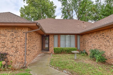 Doorway to property with a shingled roof and brick siding