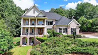 View of front of home with a balcony, brick siding, a front lawn, and a porch