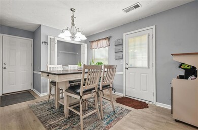 Dining space with a chandelier, light wood-type flooring, and a textured ceiling