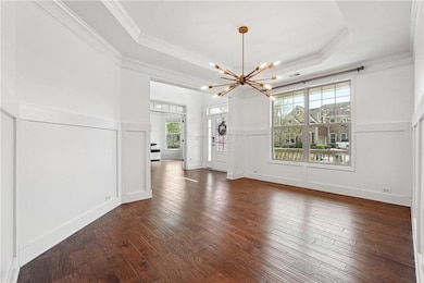 Foyer featuring crown molding, a tray ceiling, a chandelier, and a decorative wall