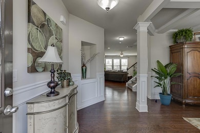 Foyer featuring decorative columns, a wainscoted w