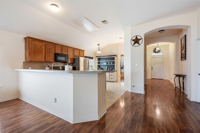 Kitchen featuring arched walkways, brown cabinetr