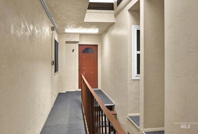 Hallway featuring a textured wall, dark carpet, and an upstairs landing