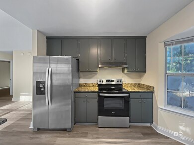 Kitchen featuring stainless steel appliances, light wood-type flooring, gray cabinetry, and dark stone counters