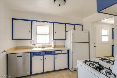 Kitchen with white fridge, stainless steel dishwasher, light tile patterned flooring, range, and sink
