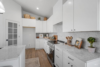Kitchen with stainless steel range with electric cooktop, wood finished floors, white cabinets, and recessed lighting