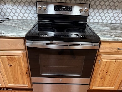 Kitchen with stainless steel electric range oven and decorative backsplash
