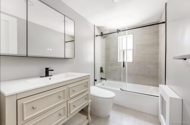 Bathroom with bath / shower combo with glass door, vanity, and radiator