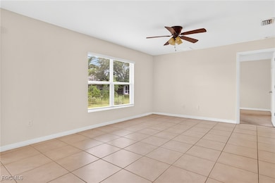 Empty room featuring ceiling fan and light tile pa