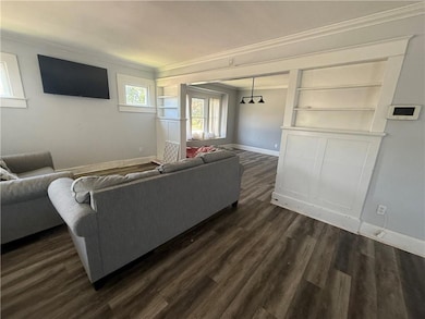 Living room featuring crown molding, dark wood-style flooring, and built in features