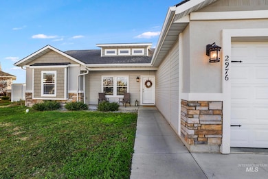 Doorway to property featuring stone siding, a yard, and a shingled roof