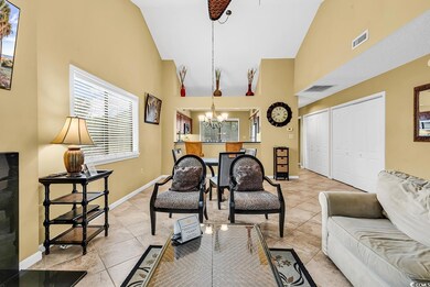 Living area featuring high vaulted ceiling, a chandelier, light tile patterned floors, and healthy amount of natural light