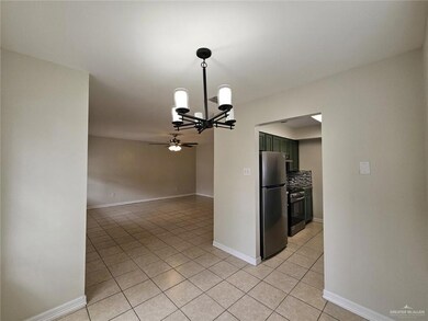 Kitchen featuring appliances with stainless steel finishes, light tile patterned flooring, ceiling fan, a chandelier, and baseboards