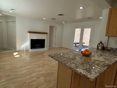 Kitchen with light stone counters, a peninsula, recessed lighting, light wood-style floors, and a fireplace