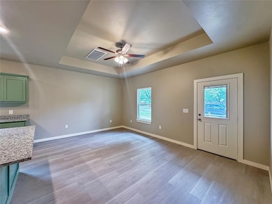 Bright living area featuring ceiling with fan, neutral walls, and wood-style flooring.Note: Photos are of a similar home by the builder.