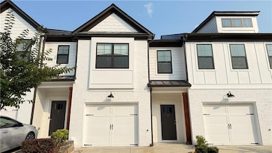 Townhome / multi-family property featuring a garage and brick siding