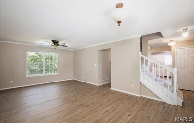 Unfurnished living room with ornamental molding, wood finished floors, stairway, and a ceiling fan