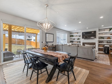 Dining room with a fireplace, wood finished floors, a textured ceiling, a chandelier, and recessed lighting